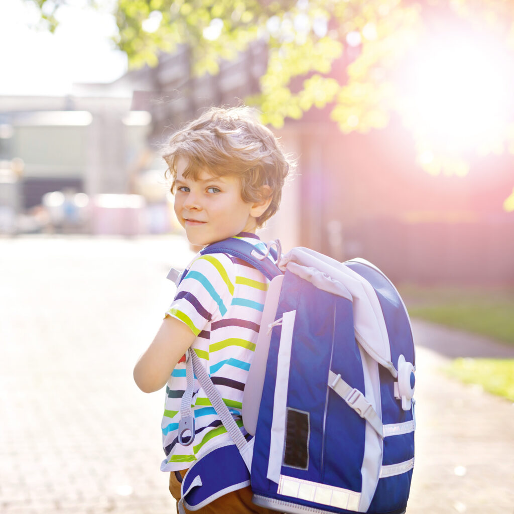 Kind mit Schulranzen auf dem Weg zur Schule