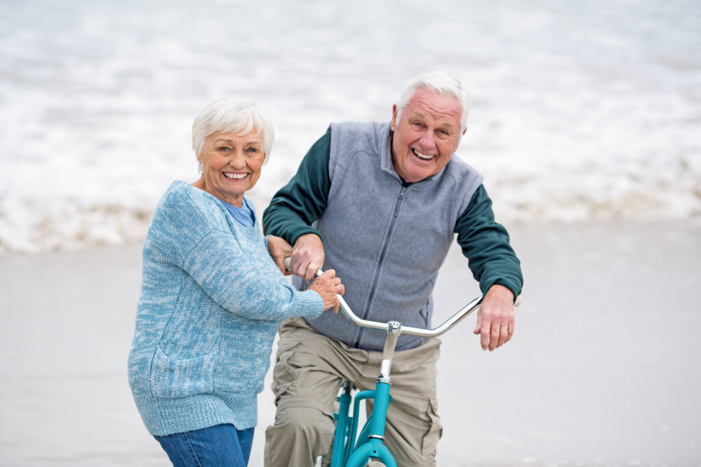 Lachendes Senioren Paar beim Radfahren am Strand