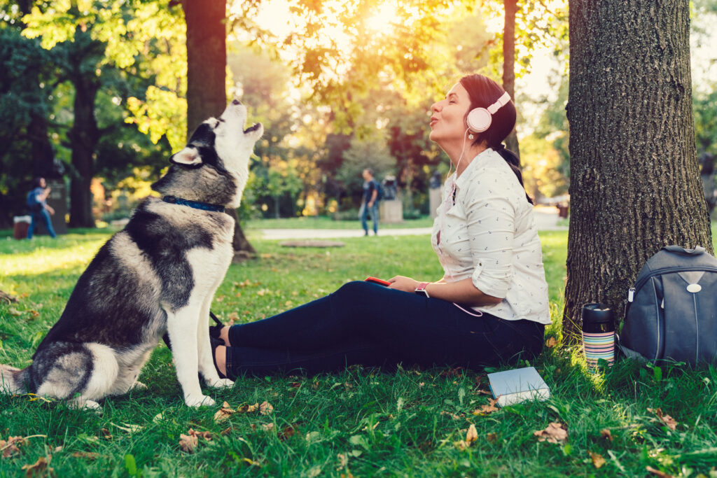 Frau mit Hund im Park beim gemeinsamen Singen